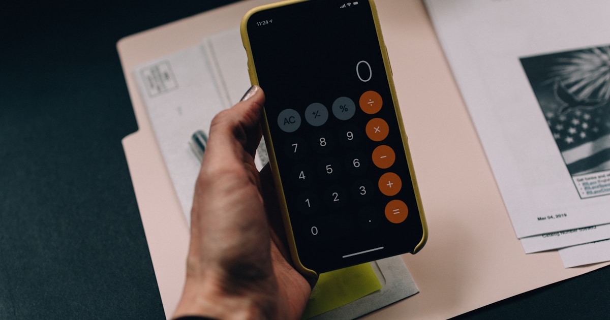 Calculator app on a phone over a desk with financial paperwork