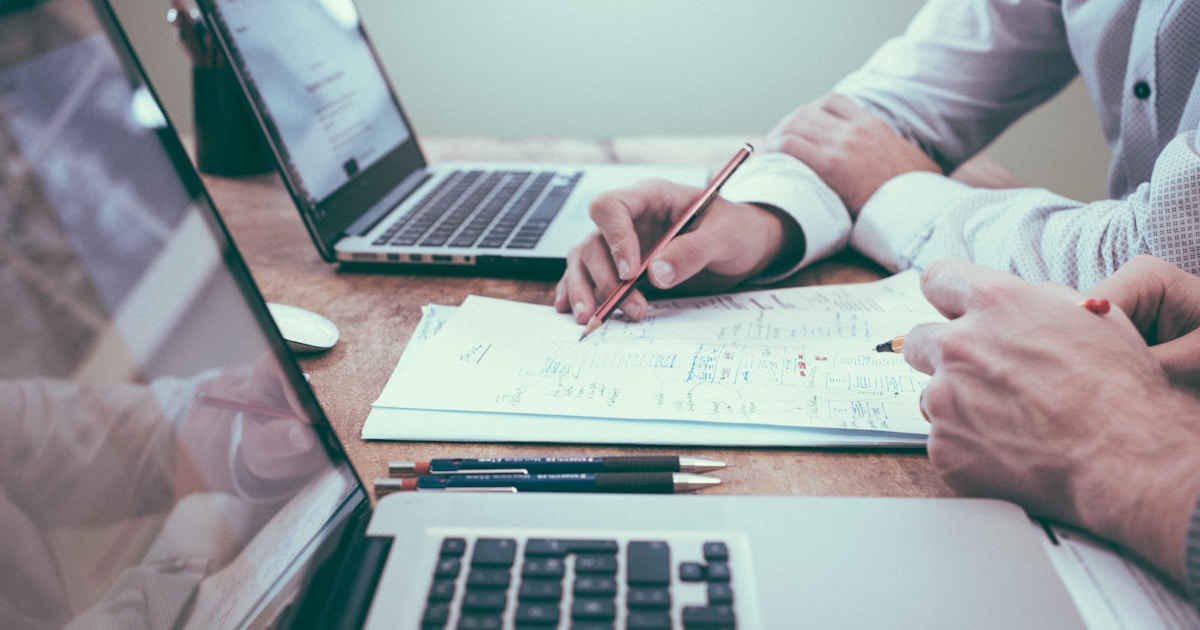 People planning a budget with notes and laptops on a desk