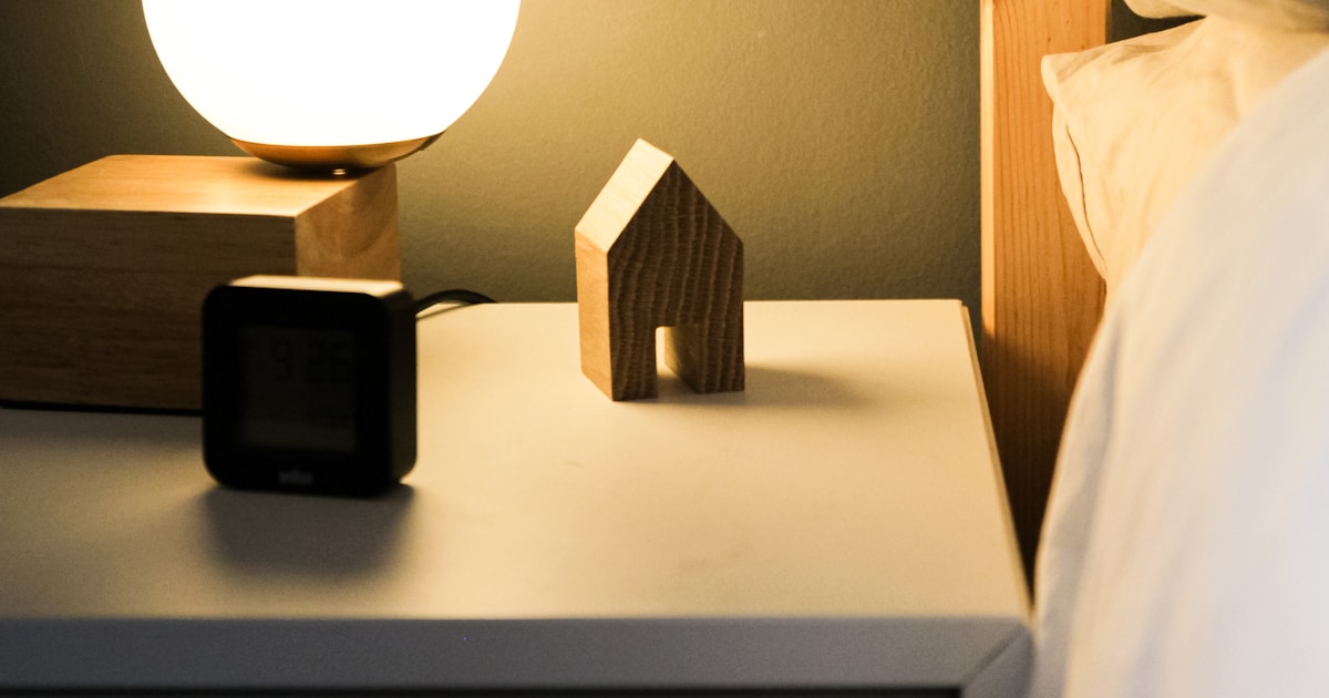 Alarm clock on a bed beside a sleeping person