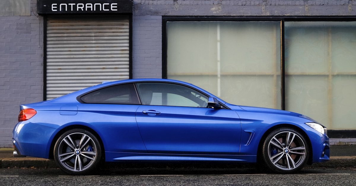 Blue sports car parked on a street with the wheel and tyre visible